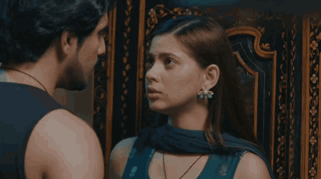 a man with a beard and a woman with red hair are looking at each other