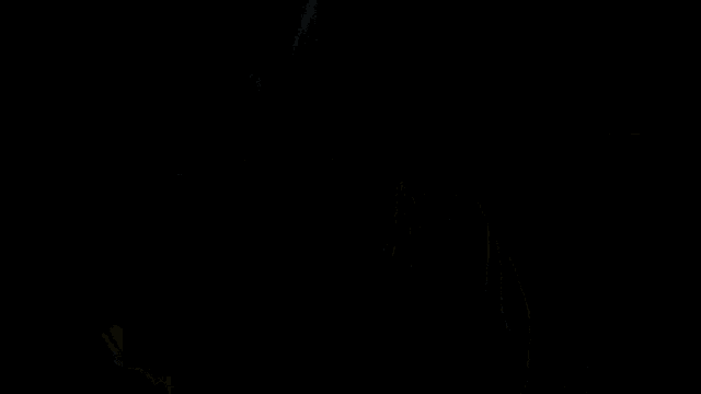 a young man is sitting in a dark room with a bottle of sprite in the background