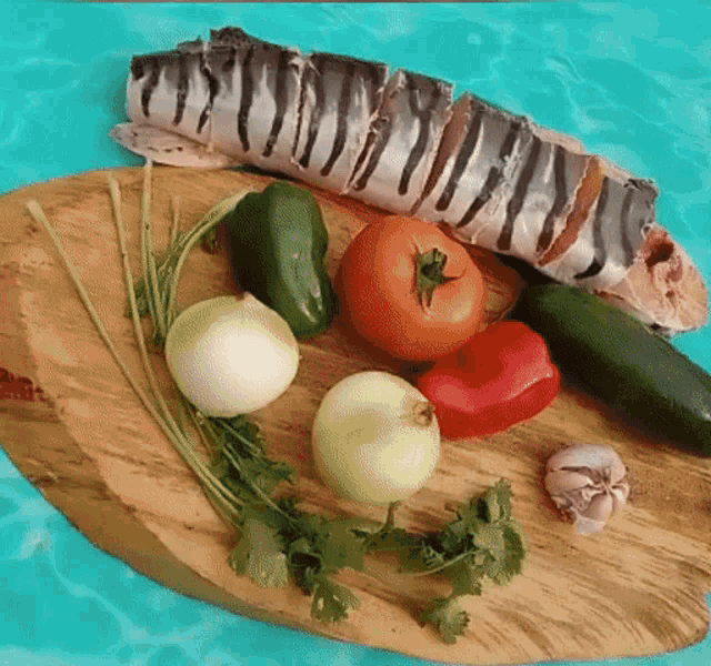 a cutting board with vegetables and a fish on top