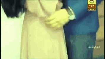 a man in a suit is holding a woman 's arm while a woman in a white dress looks on .