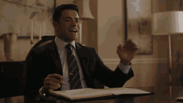 a man in a suit and tie sits at a desk