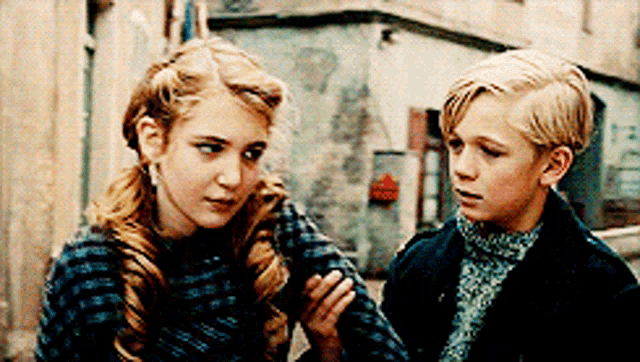 a boy and a girl are standing next to each other on a sidewalk .
