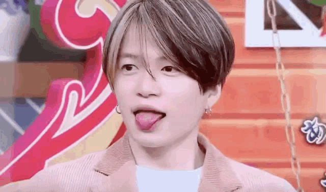 a young man is sticking his tongue out in front of a colorful wall .