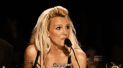 britney spears is giving a speech in front of a microphone and says `` girl power '' .