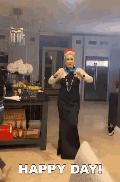 a woman in a long black dress is dancing in a kitchen with the words happy day written below her