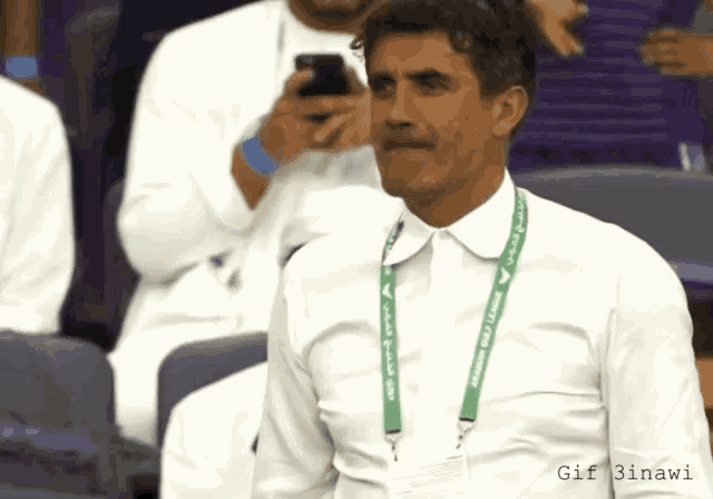 a man in a white shirt has a green lanyard around his neck that says ' saudi arabia '