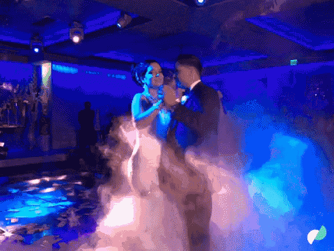 a bride and groom are dancing in front of a blue light