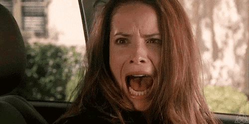 a woman is screaming while sitting in a car with her mouth open .