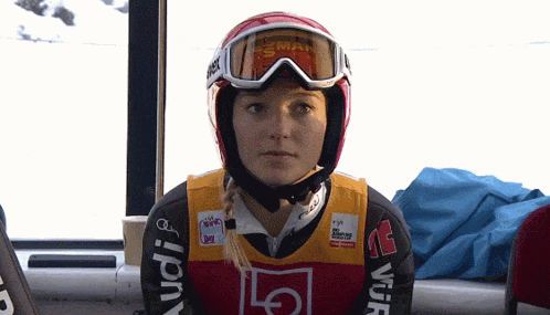 a woman wearing a helmet and goggles has an audi logo on her sleeve