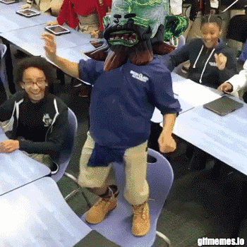 a man with a mask on his head is dancing in front of a group of kids