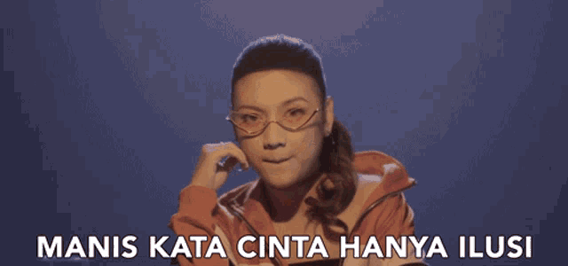 a woman wearing glasses and a red jacket says manis kata cinta hanya illusi