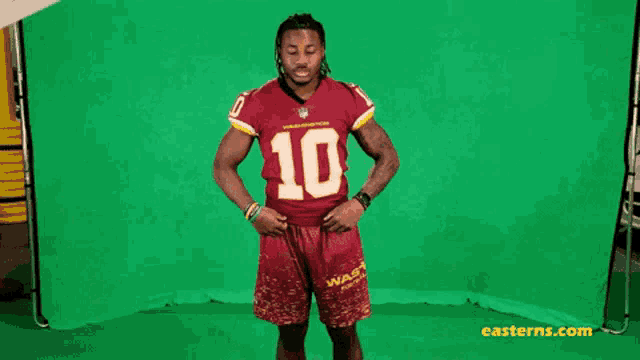 a man wearing a washington redskins jersey and shorts stands in front of a green screen