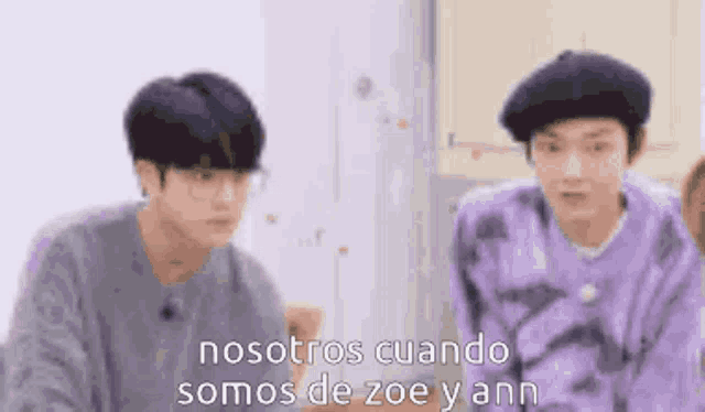 two young men are standing next to each other in a kitchen and talking to each other .