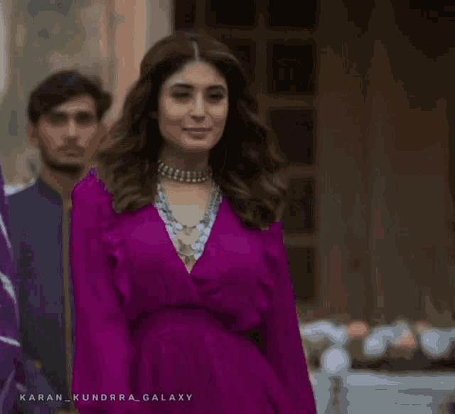 a woman in a purple dress is walking with a man in a tie dye shirt