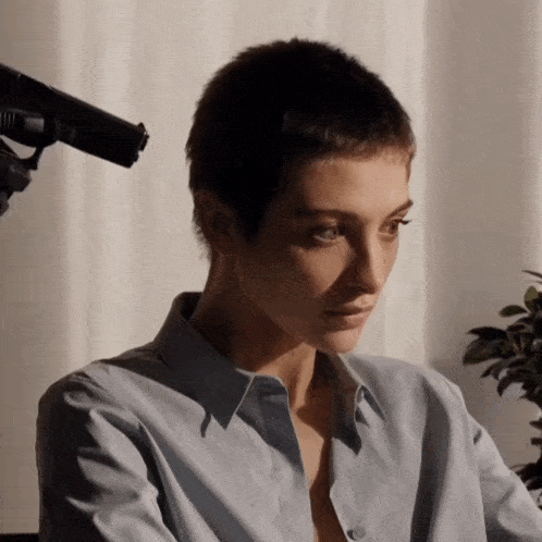 a woman wearing a blue shirt is sitting in front of a microphone