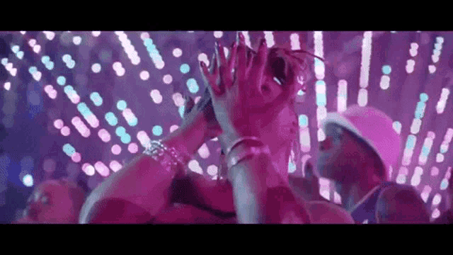 a woman with long nails is dancing in front of a crowd at a party in a club .
