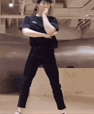 a young man in a black shirt and black pants is dancing in a room .
