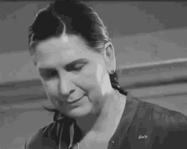 a black and white photo of a woman 's face with a necklace around her neck .