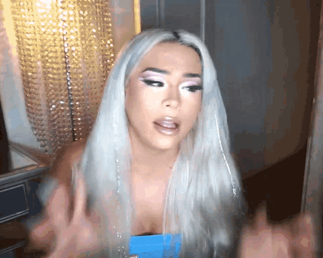 a woman with white hair and pink eyeshadow is talking