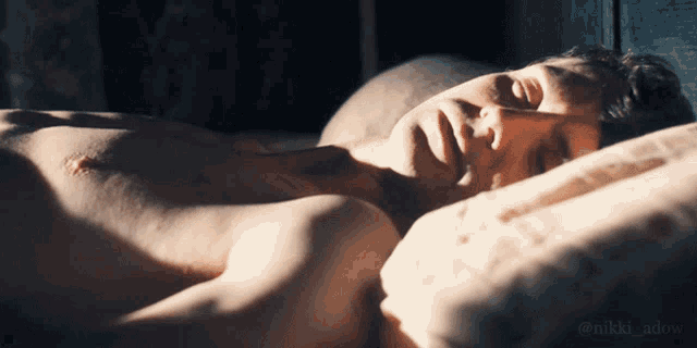 a shirtless man laying on a bed with his eyes closed and the hashtag @nikki_adow