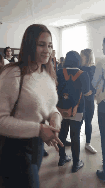 a girl in a white sweater is standing in a crowd