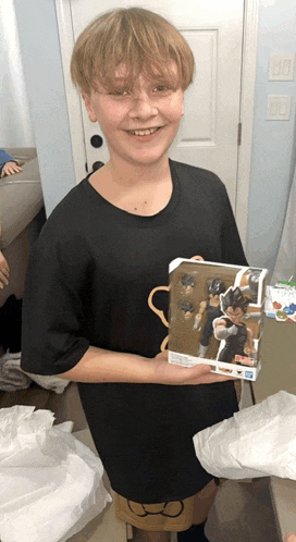 a boy in a black shirt is holding a box with a figurine on it
