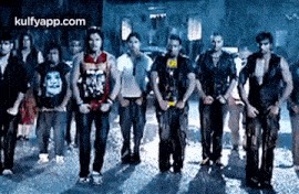 a group of young men are standing next to each other on a street in a dark room .