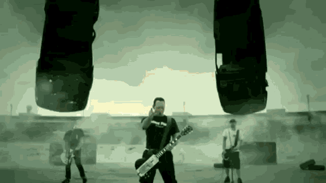 a man is playing a guitar while two cars are flying in the air behind him .