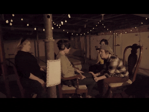 a group of people are sitting around a table with a man wearing headphones