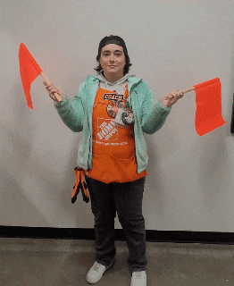 a woman wearing a home depot apron holds up two red flags