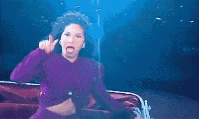 a woman in a purple dress is dancing on a stage in a club .