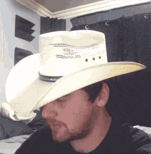 a man wearing a white cowboy hat looks down at something