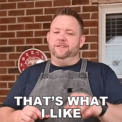 a man in an apron says that 's what i like while holding a piece of meat .