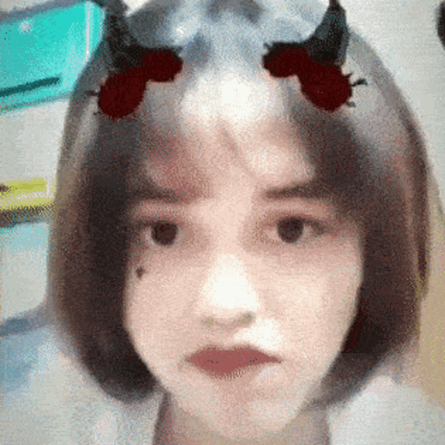 a close up of a woman 's face with horns on her hair