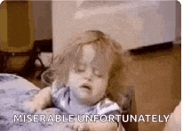 a baby is laying on a bed with his eyes closed and a caption that says `` miserable unfortunately '' .
