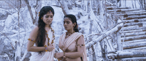 a couple of women standing next to each other in a snowy forest
