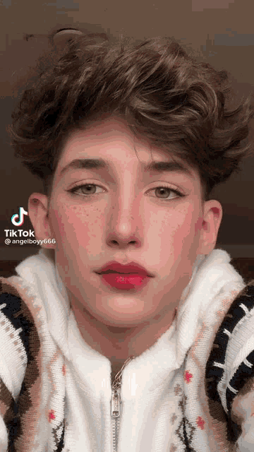 a young man with red lips and freckles is wearing a sweater