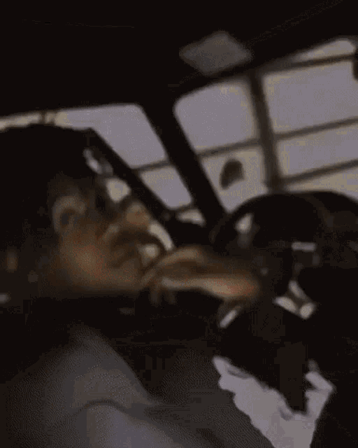 a man is driving a car with his hand on the steering wheel .