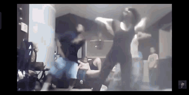 a group of people are dancing in a living room in front of a ceiling fan .