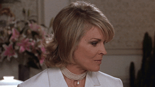 a woman wearing a pearl necklace and a white suit