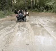 a group of people are riding atvs down a dirt road .