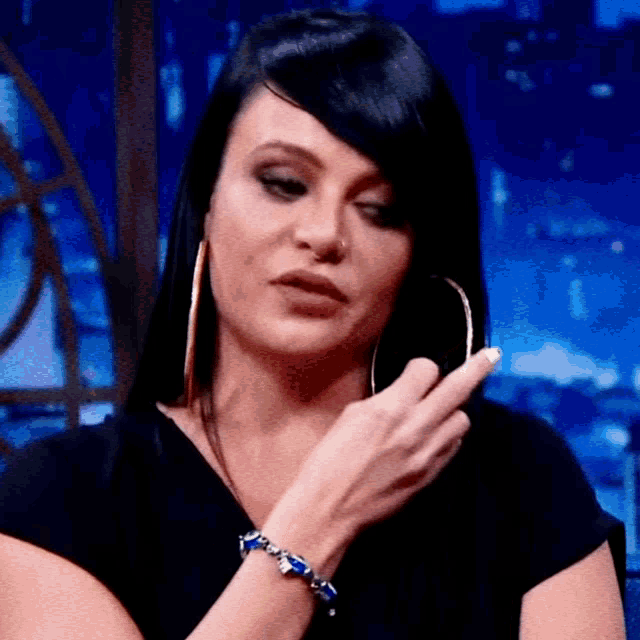 a woman wearing hoop earrings and a bracelet on her wrist