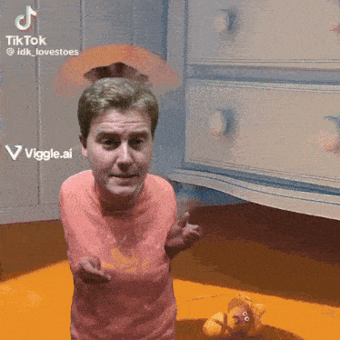 a man in a pink shirt is standing in front of a white dresser and a teddy bear with googly eyes