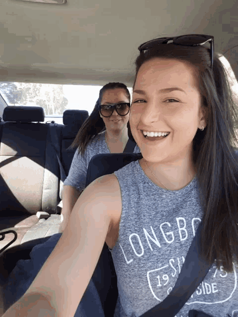 a woman wearing a long beach shirt is smiling in the back seat of a car