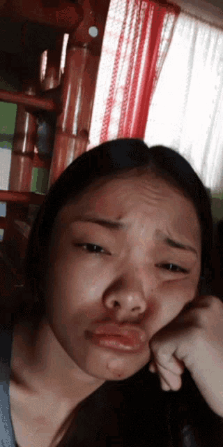 a woman making a face with her hand on her chin