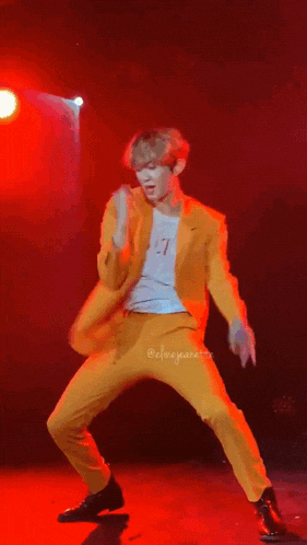 a man wearing a yellow suit and a white t-shirt with the word vltn on it