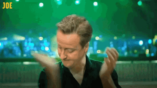 a man in a black shirt is clapping in front of a green background with the letters joe on it