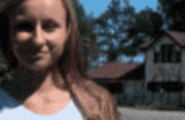 a woman is smiling in front of a house