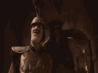 a man in armor is standing next to a robot with a sword .