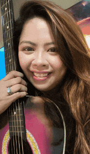 a woman is smiling while holding a guitar
